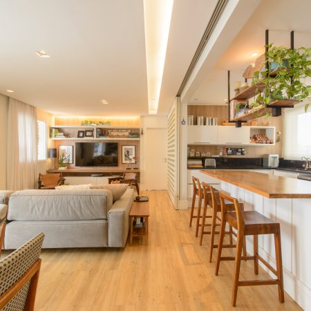 Sala com cozinha integrada e piso vinílico LVT madeirado, ilha com banquetas de madeira. Projeto de Lilian Melo Arquitetura, fotos: Edson Ferreira